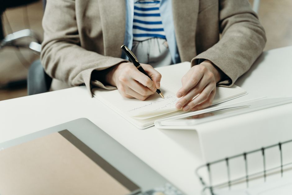 Close-up de una persona escribiendo en un cuaderno en un escritorio moderno de oficina